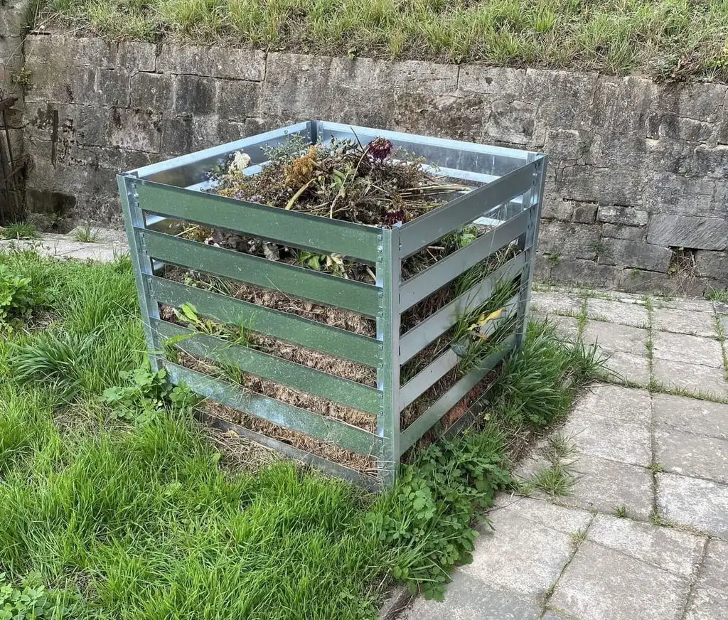Metallkomposter mit Gartenabfällen wie Laub und Rasenschnitt befüllt.